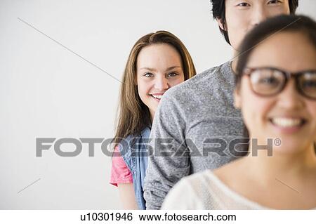 Portrait of young man standing between young women View Large Photo Image Stock Photograph - Portrait of young man standing between young women. Fotosearch