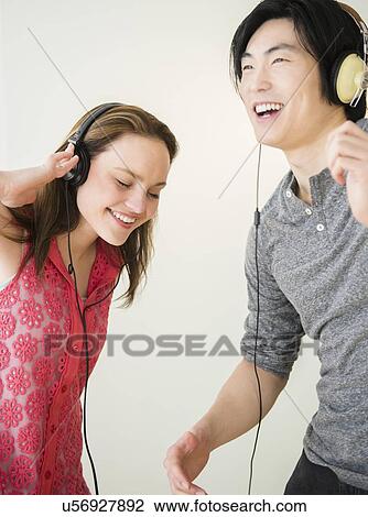 Portrait of young woman and man listening to music on MP3 player View Large Photo Image Stock Image - Portrait of young woman and man listening to music on MP3 player. Fotosearch