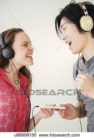 Portrait of young woman and man listening to music on MP3 player View Large Photo Image Stock Image - Portrait of young woman and man listening to music on MP3 player. Fotosearch