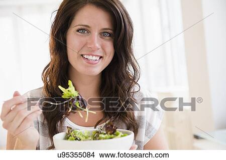 Picture - Portrait of young woman eating fresh salad. Fotosearch