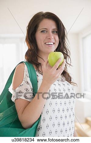 Picture - Portrait of young woman holding green apple. Fotosearch