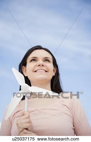 Stock Photography - Portrait of young woman holding minature wind turbine. Fotosearch