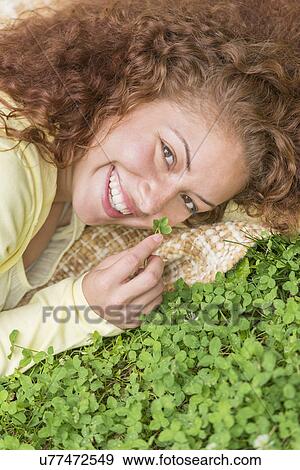 Stock Photo - Portrait of young woman lying on grass in park. Fotosearch