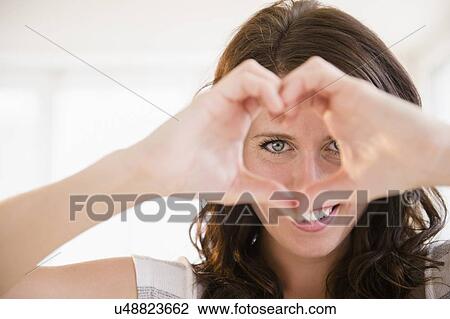 Portrait of young woman making heart shape with her hands View Large Photo Image Stock Image - Portrait of young woman making heart shape with her hands. Fotosearch