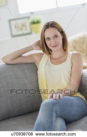 Stock Photo - Portrait of young woman relaxing on sofa. Fotosearch