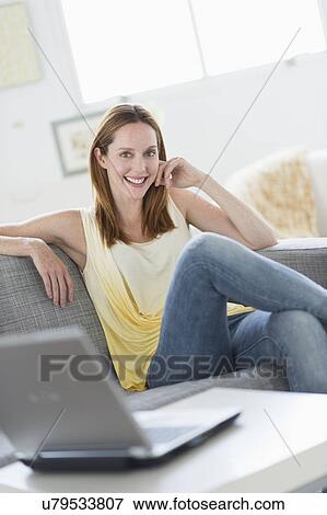 Portrait of young woman relaxing on sofa View Large Photo Image Stock Photo - Portrait of young woman relaxing on sofa. Fotosearch