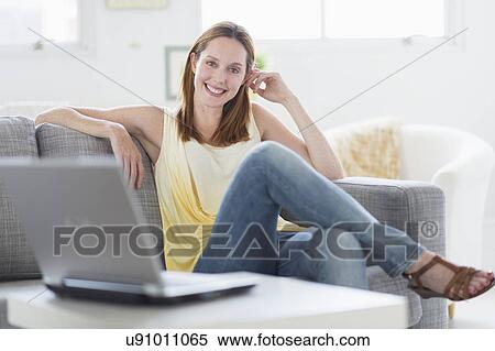 Stock Photography - Portrait of young woman relaxing on sofa. Fotosearch