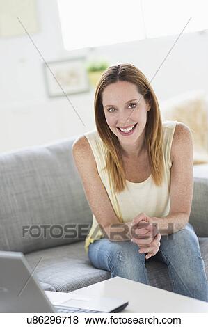 Portrait of young woman sitting on sofa View Large Photo Image Stock Photo - Portrait of young woman sitting on sofa. Fotosearch