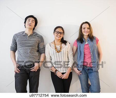 Picture - Portrait of young women and man against white wall. Fotosearch