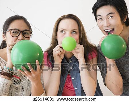 Portrait of young women and man blowing green balloons View Large Photo Image Stock Photography - Portrait of young women and man blowing green balloons. Fotosearch