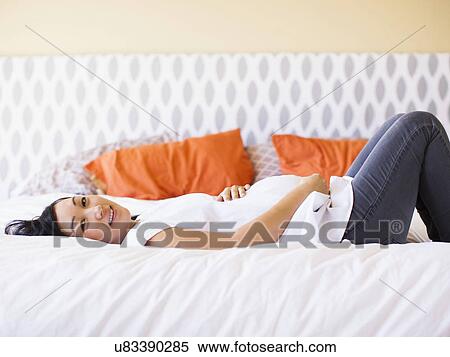 Pregnant woman lying on bed View Large Photo Image Stock Photography - Pregnant woman lying on bed. Fotosearch