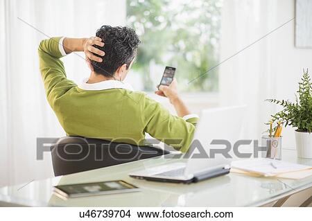Picture - Rear view of man using mobile phone. Fotosearch