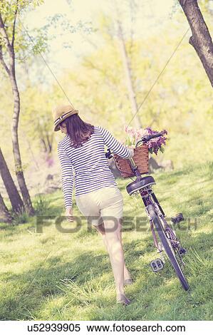 Rear view of mid adult woman with bicycle View Large Photo Image Stock Photography - Rear view of mid adult woman with bicycle. Fotosearch
