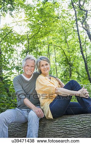 Senior couple sitting on log in forest View Large Photo Image Stock Photo - Senior couple sitting on log in forest. Fotosearch