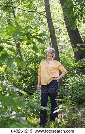 Stock Image - Senior woman hiking in forest. Fotosearch