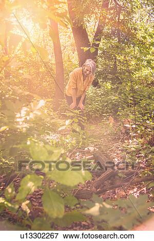 Stock Photo - Senior woman hiking in sunny forest. Fotosearch