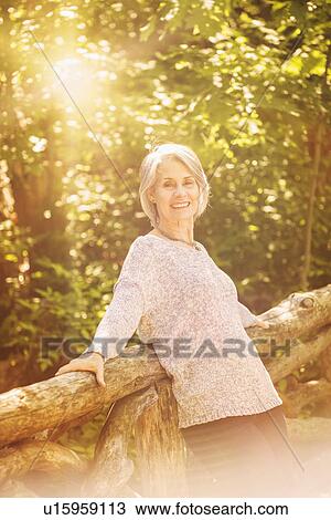 Stock Image - Senior woman relaxing in park. Fotosearch