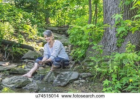 Senior woman sitting by stream View Large Photo Image Picture - Senior woman sitting by stream. Fotosearch