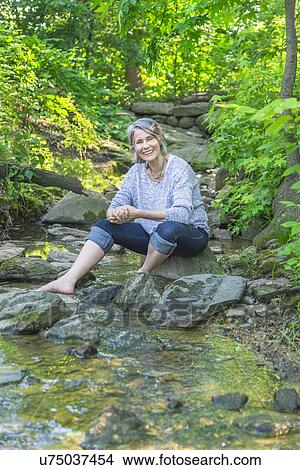 Senior woman sitting by stream View Large Photo Image Picture - Senior woman sitting by stream. Fotosearch
