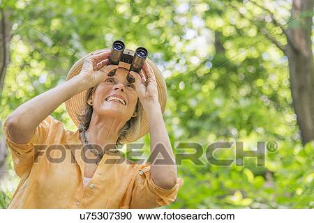 Senior woman with binoculars in park View Large Photo Image Stock Image - Senior woman with binoculars in park. Fotosearch