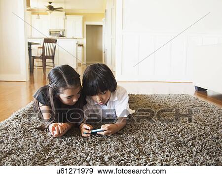 Stock Photo - Siblings (8-9) playing mobile phone game. Fotosearch