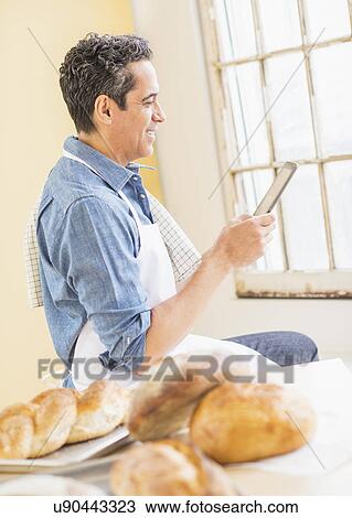 Side view of baker using digital tablet View Large Photo Image Stock Image - Side view of baker using digital tablet. Fotosearch
