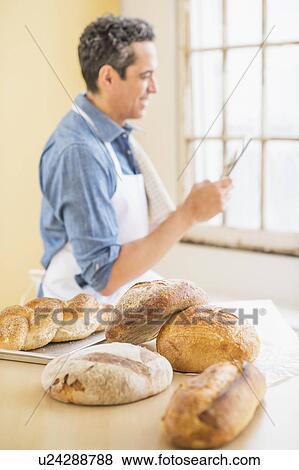 Side view of baker using digital tablet View Large Photo Image Stock Photo - Side view of baker using digital tablet. Fotosearch
