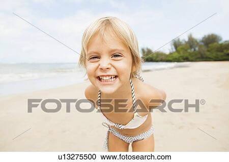 Stock Image - Smiling girl (2-3) on sandy beach. Fotosearch