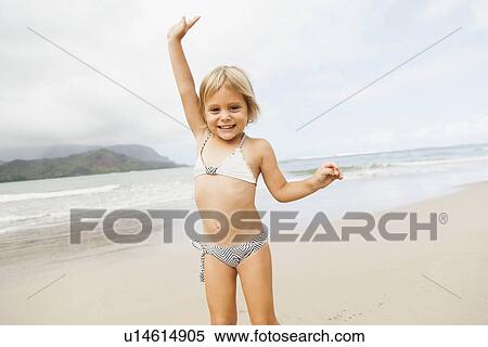 Stock Photography - Smiling girl (2-3) on sandy beach. Fotosearch