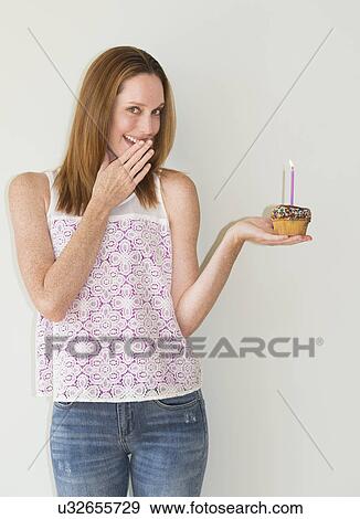 Studio portrait of woman holding birthday cupcake View Large Photo Image Stock Photo - Studio portrait of woman holding birthday cupcake. Fotosearch