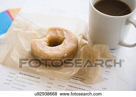 Stock Photo - Studio Shot coffee and donut on documents. Fotosearch