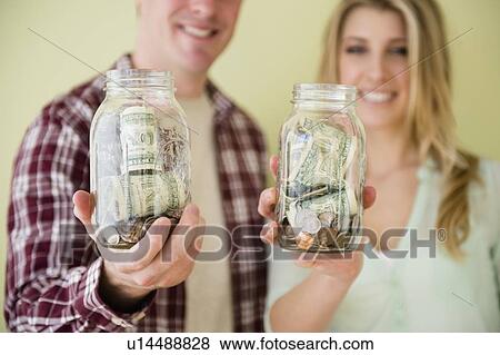 Stock Photo - Studio shot of couple holding jars with money. Fotosearch