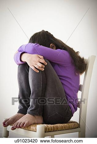 Studio shot of sad girl (8-9) curling on chair View Large Photo Image Stock Image - Studio shot of sad girl (8-9) curling on chair. Fotosearch