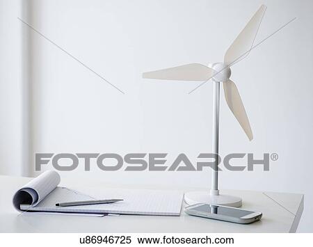 Stock Photography - Studio Shot of small wind turbine, mobile phone and note pad on desk. Fotosearch