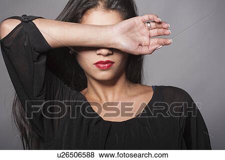 Stock Photo - Studio shot of young woman covering her face. Fotosearch