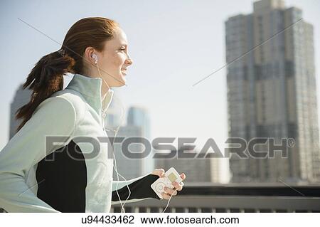 Stock Image - Teenage girl (14-15) jogging in city. Fotosearch