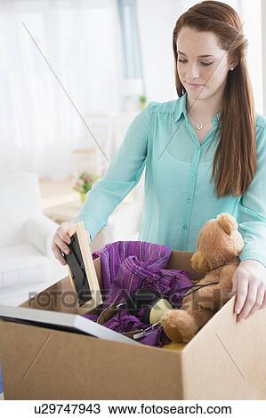 Stock Image - Teenage girl (14-15) with cardboard box. Fotosearch