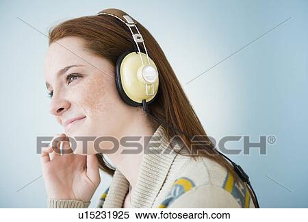 Stock Photography - Teenage girl (14-15) with headphones, studio shot. Fotosearch
