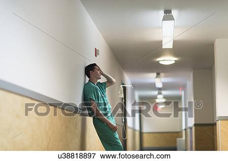 Stock Photo - Tired doctor standing in hallway. Fotosearch