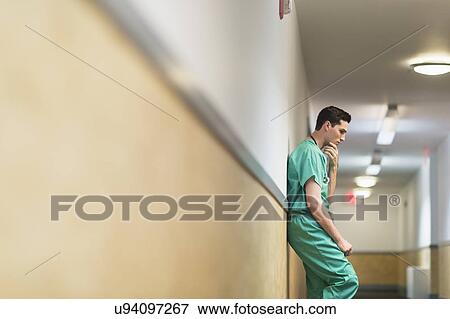 Stock Photo - Tired doctor standing in hallway. Fotosearch