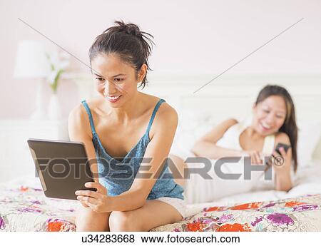 Stock Photo - Two women using digital tablet and mobile phone. Fotosearch