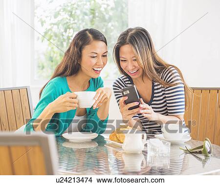 Picture - Two women using mobile phone. Fotosearch