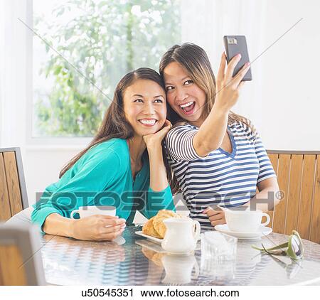 Two women using mobile phone View Large Photo Image Stock Image - Two women using mobile phone. Fotosearch