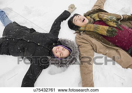 Stock Image - Two young people making snow angels. Fotosearch