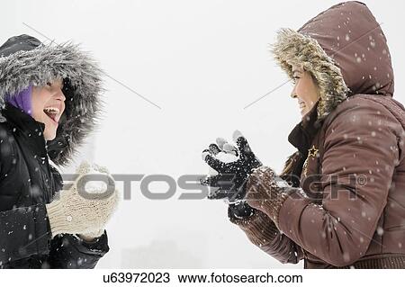 Stock Image - Two young women having snowball flight . Fotosearch