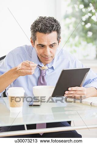 View of mature man eating cereal and using digital tablet View Large Photo Image Stock Image - View of mature man eating cereal and using digital tablet. Fotosearch