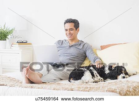 Picture - View of mature man using laptop at home. Fotosearch