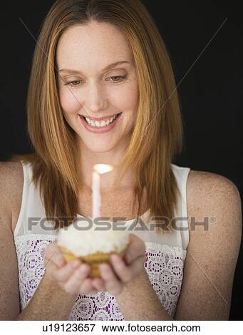Stock Photo - Woman holding birthday cupcake. Fotosearch