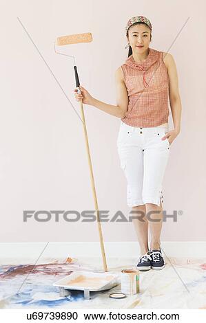 Stock Image - Woman holding paint roller. Fotosearch