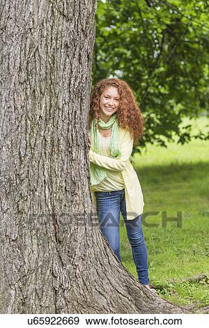 Woman leaning on tree in park View Large Photo Image Stock Photo - Woman leaning on tree in park. Fotosearch